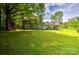 Green backyard showcasing a two-story home, lush lawn, mature trees, and a convenient covered parking area at 3400 Tracelake Dr, Matthews, NC 28105