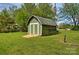 Green shed with a gray roof sits on a well-manicured lawn, blending functionality with backyard aesthetics at 3400 Tracelake Dr, Matthews, NC 28105