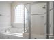 Bright bathroom showcasing a jacuzzi tub, and a glass-enclosed shower with tiled walls at 3516 Araglin Dr, Gastonia, NC 28056