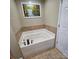 Bathroom with a garden tub surrounded by tile, neutral walls, tile floors, and a white door at 4210 Runaway Cir, Monroe, NC 28110