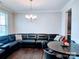 Cozy living room with a black sectional sofa, hardwood floors, and a modern chandelier at 4253 Stream Dale Nw Cir, Concord, NC 28027