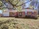 Charming brick home with red shutters and blooming tree in the front yard on a sunny day at 4401 Coachwood Ln, Gastonia, NC 28056