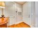 Entryway view with two white doors, hardwood floor, and wood side table with lamp at 4620 Piedmont Row Dr # 605, Charlotte, NC 28210