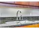 Close-up of the kitchen sink and faucet surrounded by dark granite countertops and wood cabinets at 4620 Piedmont Row Dr # 605, Charlotte, NC 28210
