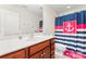 Cozy bathroom with wooden vanity, white porcelain sink, toilet, and anchor-themed shower curtain at 4858 Sagittarius Cir, Denver, NC 28037