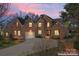 Stunning brick home featuring a well-manicured lawn, 3 car garage and lush landscaping against a picturesque evening sky at 4858 Sagittarius Cir, Denver, NC 28037