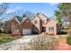 Stunning brick home featuring a well-manicured lawn, 3 car garage and lush landscaping against a bright blue sky at 4858 Sagittarius Cir, Denver, NC 28037