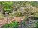 Lush backyard garden featuring mature trees, flowering shrubs, and stone pathway at 5114 Morrowick Rd, Charlotte, NC 28226