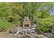 Outdoor stone fireplace and chairs create a cozy spot within a lush, green landscape at 5114 Morrowick Rd, Charlotte, NC 28226