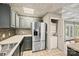 Well-equipped kitchen featuring stainless steel refrigerator, gray cabinets, and convenient in-unit laundry at 8014 Kiwi Pt, Tega Cay, SC 29708