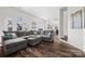 Spacious living room with a plush gray sectional, hardwood floors, and abundant natural light at 8014 Kiwi Pt, Tega Cay, SC 29708