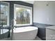 Bright bathroom featuring a sleek soaking tub beneath a window with natural light and tiled accent wall at 8201 Tonawanda Dr, Charlotte, NC 28277