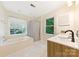 Bright bathroom featuring a double sink vanity, a tub and shower combination with windows at 9423 Fairmead Dr, Charlotte, NC 28269