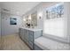 Bright bathroom featuring double vanity, elegant mirrors, and a seating area near the window at 101 Woodvale Cir, Lincolnton, NC 28092