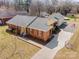 Aerial view of a well-maintained brick home with a manicured lawn, paved driveway, and an American flag at 11018 Despa Dr, Mint Hill, NC 28227