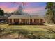 Charming single-story brick home with manicured lawn and mature trees, bathed in the warm glow of the setting sun at 11018 Despa Dr, Mint Hill, NC 28227