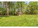 A rustic shed sits in a lush green yard surrounded by mature trees, offering additional storage or workspace at 123 Lucy Ln, Statesville, NC 28625