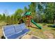 Landscaped backyard featuring a playset, a fire pit, mature trees, and a seating area at 12915 Settlers Trail Ct, Charlotte, NC 28278