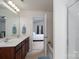 Bathroom with a double sink vanity and view to the bedroom with neutral colors and a tub at 12915 Settlers Trail Ct, Charlotte, NC 28278