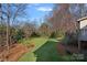 The backyard features a lush lawn, mature trees and plants, mulch beds, and a wooden deck on the back of the house at 1624 Chadmore Nw Ln, Concord, NC 28027