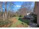 The backyard features a lush lawn, mature trees and plants, and a wooden deck on the back of the house at 1624 Chadmore Nw Ln, Concord, NC 28027