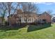 Rear exterior view of brick home with screened porch, deck and manicured backyard with mature trees at 1624 Chadmore Nw Ln, Concord, NC 28027
