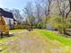 Expansive backyard featuring lush green grass, mature trees, and a cozy fire pit area at 3016 Hanson Dr, Charlotte, NC 28207
