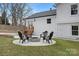 Outdoor fire pit with chairs surrounded by green grass, leading to back of renovated home at 437 Chadmore Dr, Charlotte, NC 28270