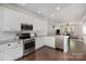 Modern kitchen featuring white cabinets, stainless steel appliances, granite countertops, and open access to the living room at 464 Hurston Cir, Charlotte, NC 28208