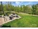 Spacious backyard featuring a stone patio with a fire pit and seating area, surrounded by lush greenery at 5140 Oak Grove Pl, Waxhaw, NC 28173