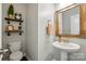 Charming half bathroom with stylish mirror, pedestal sink, decorative shelves, and warm lighting at 5140 Oak Grove Pl, Waxhaw, NC 28173