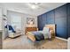 Cozy bedroom with blue accent wall, natural wood bed frame, dresser and a comfortable chair at 5140 Oak Grove Pl, Waxhaw, NC 28173