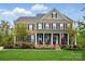 Charming brick home featuring a welcoming front porch with rocking chairs and an American flag at 5140 Oak Grove Pl, Waxhaw, NC 28173