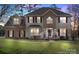 Charming two-story home featuring a brick facade, manicured lawn, and inviting entryway with red shutters and flower pots at 7510 Plumcrest Ln, Harrisburg, NC 28075