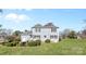 Backyard with grassy lawn, mature trees, and two-story home with grey siding at 9218 Robert Burns Ct, Charlotte, NC 28213
