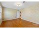 A bedroom with hardwood flooring, vintage floral wallpaper, and natural light at 9218 Robert Burns Ct, Charlotte, NC 28213