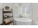Bright bathroom featuring a freestanding tub, shelving, and natural light from the large windows at 123 Southhaven Dr, Mooresville, NC 28117