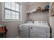 Laundry room featuring a large window, white washer and dryer, shelving, and neutral paint at 138 Margo Ln, Statesville, NC 28677