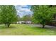 A ranch-style home with stone details is surrounded by large trees and a green lawn at 1514 Ring Tail Rd, Claremont, NC 28610