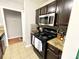 Kitchen featuring stainless steel microwave, black stove, tile floors, and dark wooden cabinets at 218 Cottonwood Park Dr, Charlotte, NC 28214