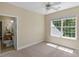 Bright bedroom with a window, ceiling fan and an open doorway leading to an ensuite bathroom at 3017 Chisholm Ct, Waxhaw, NC 28173
