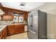 Traditional kitchen features wood cabinets, a stainless steel refrigerator, and a sink with a view at 5643 Twinkle Dr, Concord, NC 28025