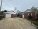 Rear exterior view of brick home with driveway, white garage door, and mature trees at 603 E Main St, Rock Hill, SC 29730