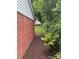 Side view showing the backyard area with brick house, grass, and foliage along fence at 603 E Main St, Rock Hill, SC 29730
