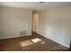 Empty living room with wood flooring and beige walls, bathed in sunlight streaming from a window at 1138 Choyce Ave, Charlotte, NC 28217