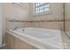 Bathroom featuring a soaking tub with tile surround and a window providing natural light at 12302 Volusia Ct, Charlotte, NC 28262