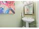 Stylish powder room with pedestal sink, elegant mirror, and decorative artwork at 1529 Indian Springs Nw Dr, Conover, NC 28613