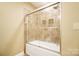 Bathroom featuring a shower over tub with a sliding glass door and a neutral tiled backsplash at 226 Hermance Ln, Mooresville, NC 28117