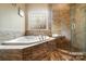 Elegant bathroom featuring a soaking tub, separate glass shower, and stylish decorative window at 226 Hermance Ln, Mooresville, NC 28117