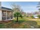 Lush backyard featuring a screened porch, patio seating area, and mature palm and flowering trees at 230 Pond View Ln, Fort Mill, SC 29715